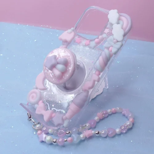 Pastel kawaii decoden phone case featuring charms of stars, bows, sweets, and a matching beaded wrist strap.