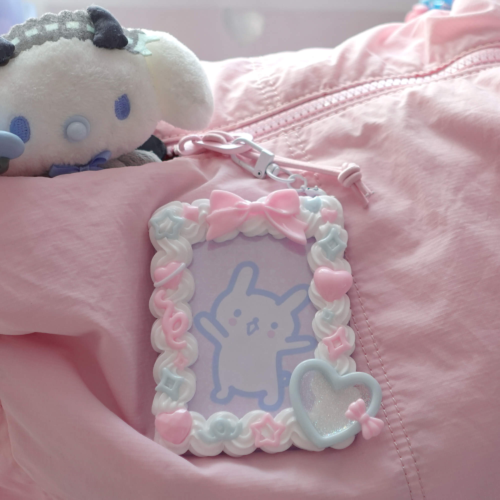 Kawaii pastel top loader photo holder attached to a pink bag, featuring a cute bunny photocard inside and surrounded by pastel hearts, bows, and star charms.